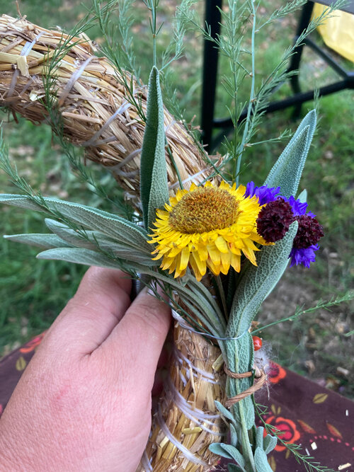 Couronne : un petit bouquet de fleurs et de feuilles est fixé sur une base en paille