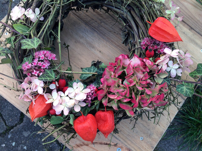 Couronne d'automne faite main avec fleurs roses, amours-en-cage orange et feuilles vertes