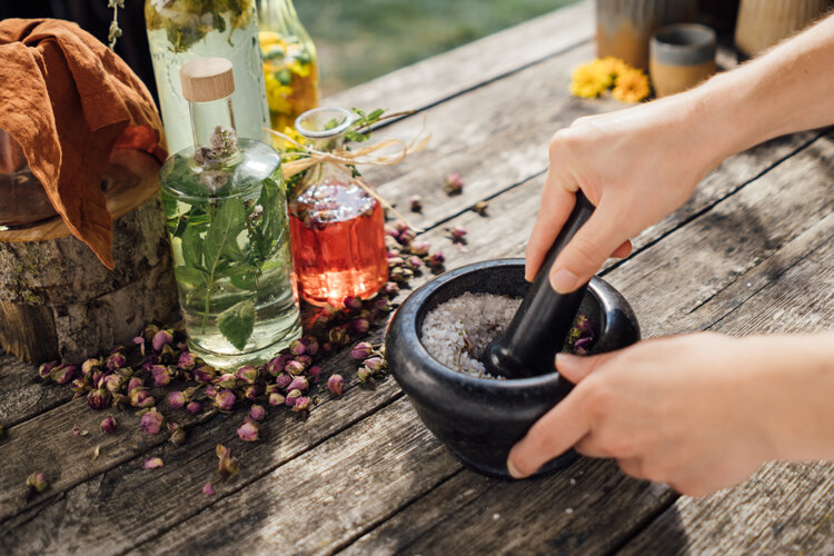 Sel aux herbes pilé dans un mortier, à côté huile aux herbes et boutons de fleurs séchés