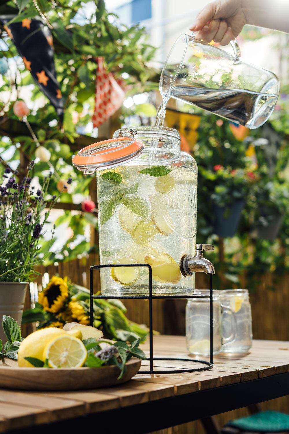 Eau versée dans une fontaine à boissons avec citron et menthe, limonade maison sur le balcon